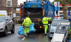 Refuse collectors carry bags to a dust cart.