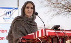 Angelia Jolie, wearing a headscarf, speaks at an outdoor lectern
