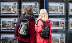 People look at properties in the window of an estate agent