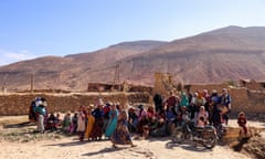 People gathered near earthen walls against a mountainous backdrop in Ighil Ntalghoumt, south of Marrakech.