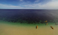 Kayakers setting off from beach into Coral Bay at Ningaloo Reef marine park, Western Australia.