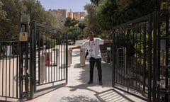 An employee shuts the exit door of the Acropolis hill archaeological site as it temporarily closes due to a heatwave