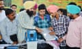 Electoral officials demonstrate how to use an electronic voting machine, which displays party symbols.