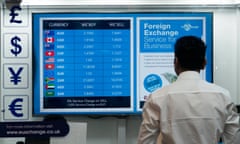 a man stares at a foreign exchange money board