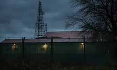 the Wethersfield military base, photographed at twilight – barracks are seen behind a high wire fence with spotlights