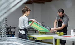 Two silk screen workers setting up the printing table.