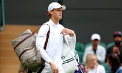 Jannik Sinner is dressed in white with a beige Gucci-branded bag on his right shoulder. A traditional white tennis bag is on his left shoulder