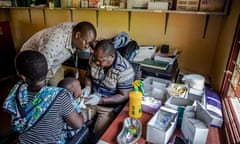 A mother holds her son while he gives blood samples to be analysed as part of a  malaria vaccine trial in Junju, Kenya.