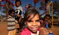 happy Aboriginal kids playing on a swing set in the main street of Amoonguna Aboriginal Community