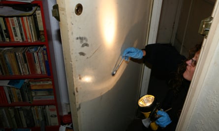 A forensic police officer dusts a door for fingerprints after a break-in at a flat