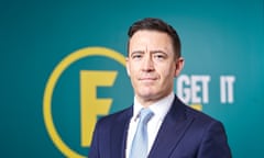 Portrait of Guy Gittins in a blue suit and grey tie, standing in front of a green and yellow Foxtons logo