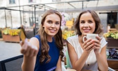 young women paying for coffee in an outdoor cafe