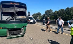 An image of a green charter bus stopped on a highway bordered by trees, with people walking around it.