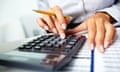 Photo of hands holding pencil and pressing calculator buttons over documents