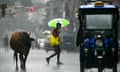 Rain-soaked commuters cross a street in Delhi.