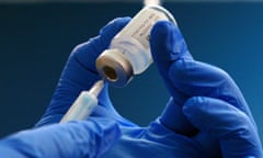 Gloved hands preparing a coronavirus vaccine