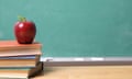 Apple On Stacked Books At Table By Green Board<br>GettyImages-686816547