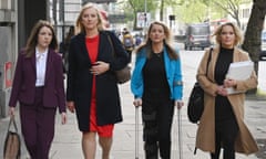 Four women walk together along a pavement