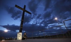 A woman sits under a cross with an anti-guns sign