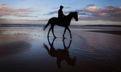 A horse and rider exercise as the sun sets on the beach at Filey.