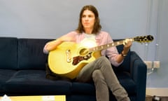 James Bay sitting on a sofa playing a guitar