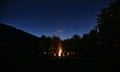 Silhouette People On Field Against Sky At Night<br>A large bonfire with people sitting around it.