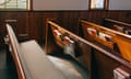 Sunlight filters through a window, casting a soft glow on the empty wooden church pews lined with hymnals