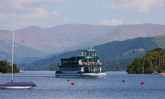 A lake steamer close to shore on a large lake flanked by beautiful rolling hills