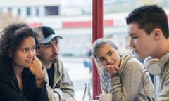 University students looking at sad friend in cafe