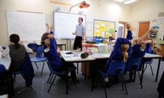 Primary school pupils working in classroom with male teacher. 