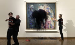 A museum guard detains one member of Last Generation Austria while the other glues his hand to the glass covering the Gustav Klimt painting.