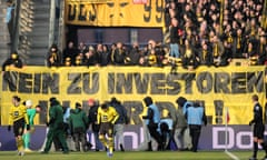 Security guards and players of Borussia Dortmund remove chocolate coins thrown on to the pitch