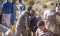 One man hugs another surrounded by men with shovels digging graves near Marrakech, Morocco