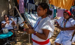 Wiwa women, in their traditional white dress, spin the yarn to weave handbags