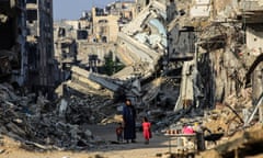 A man and his children walks past destroyed buildings in Khan Yunis on 20 June 2024.
