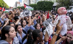 A protester holds up a doll as several thousand demonstrators show their support for Palestine by marching through Avenue Habib Bourguiba and continuing their demonstration in front of the French embassy in Tunis, Tunisia