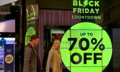 People walk past a sign advertising Black Friday offers at a perfume shop in Manchester