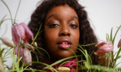 A portrait of Lolly Adefope with snake’s head fritillary flowers in front of her