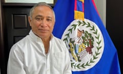 Johnny Briceño stands next to the flag of Belize