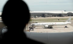 Person in silhouette viewed from behind looks at a plane on an airport runway