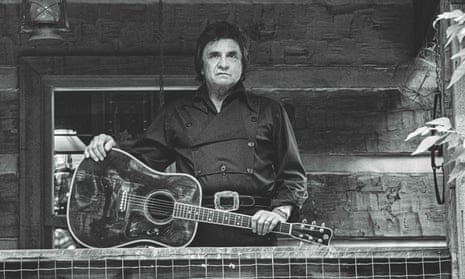 Johnny Cash on the verandah of his cabin, leaning on an acoustic guitar laid on the banister