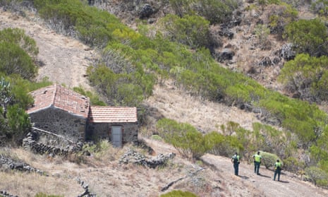 People in hi-vis jackets stand near a brick hut