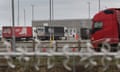 Trucks parked in a carpark with an industrial building in the background and a security barrier in the foreground