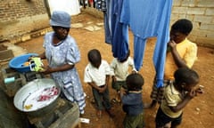 A woman washes clothes while her children play in Soweto