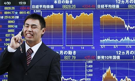 A man in Tokyo passes a board displaying a graph of the day's movement of Nikkei index in Tokyo