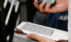 A commuter uses a Blackberry and a Kindle while riding the subway in New York