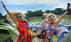 Two young women leap in the air at Glastonbury campsite