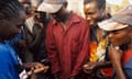 An aid worker demonstrates to a group of young men how to use a condom.