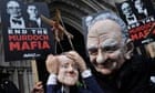 A protester wearing a mask of Rupert Murdoch holds a puppet of David Cameron