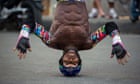 An inline-skate street performer tries to stand on his head 